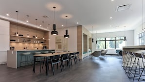 A modern kitchen with a central island, bar stools, and pendant lighting. - The Crescent (Rossland)