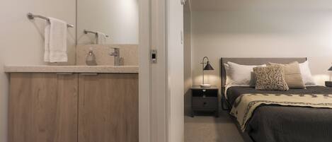 A bedroom with a bed, nightstands, a lamp, a mirror, and a wooden wardrobe.