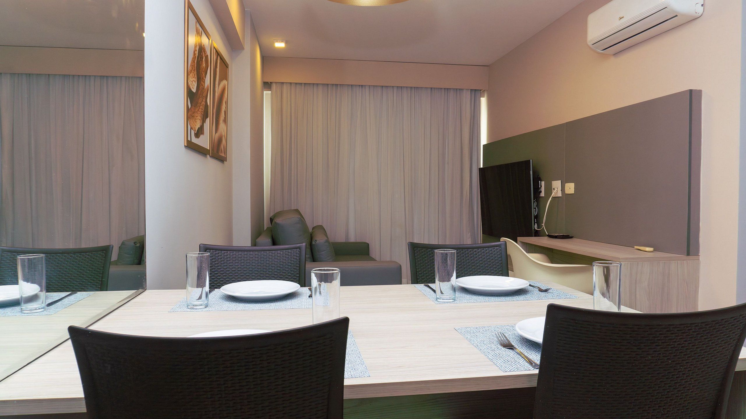 Un comedor moderno con una mesa larga, sillas y un televisor de pantalla plana montado en la pared.