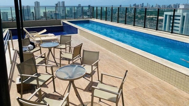 A rooftop pool with a city view, surrounded by glass railings and furnished with outdoor seating. - Beach Class Excelsior  (Recife)