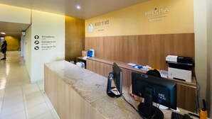 A reception desk with a sign for 'BEACH CLASS RESERVES' and a phone number. There are signs indicating elevators and garages. - Beach Class Excelsior  (Recife)
