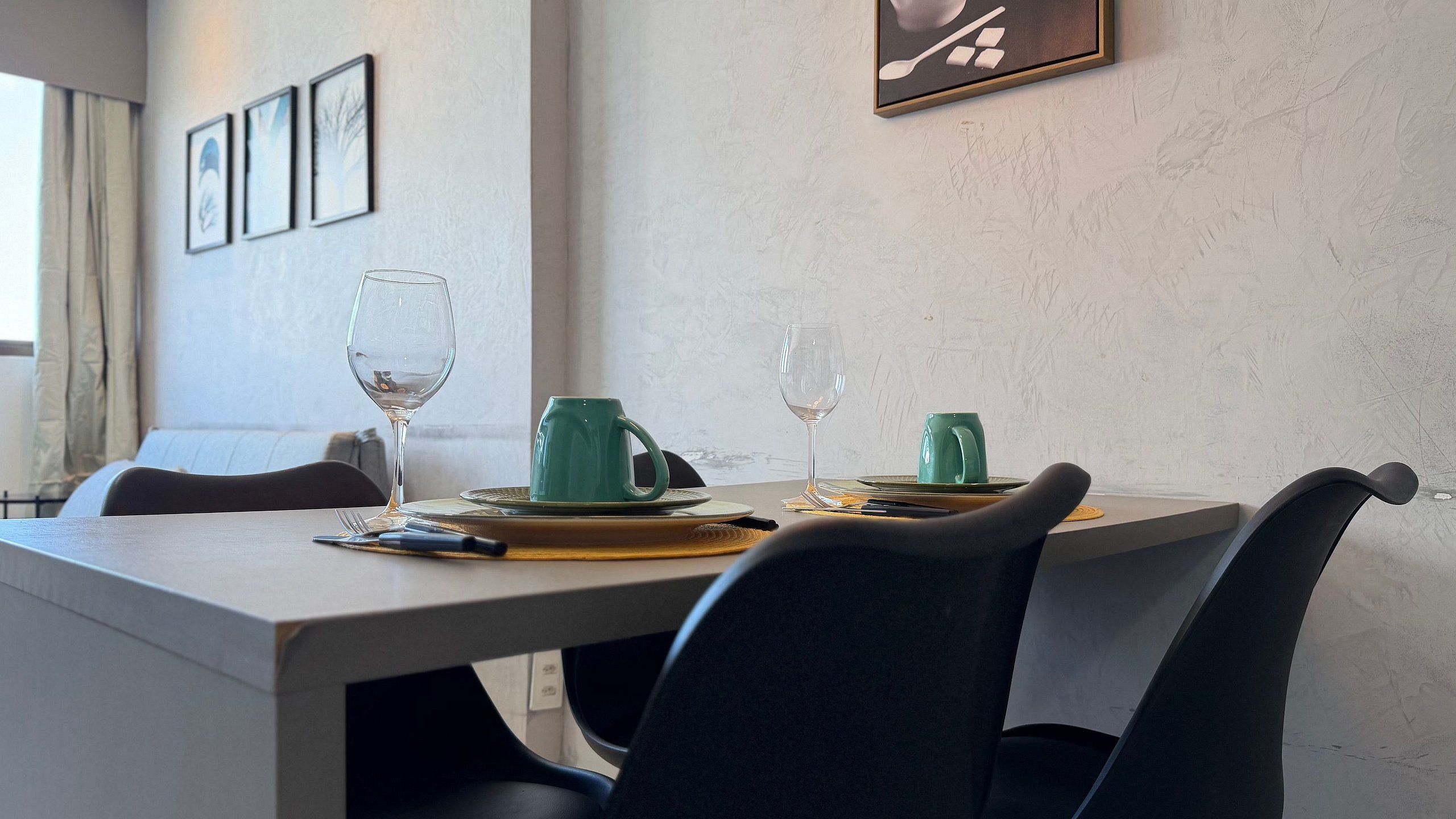 Una mesa de comedor con platos, cubiertos y vasos, rodeada de sillas.
