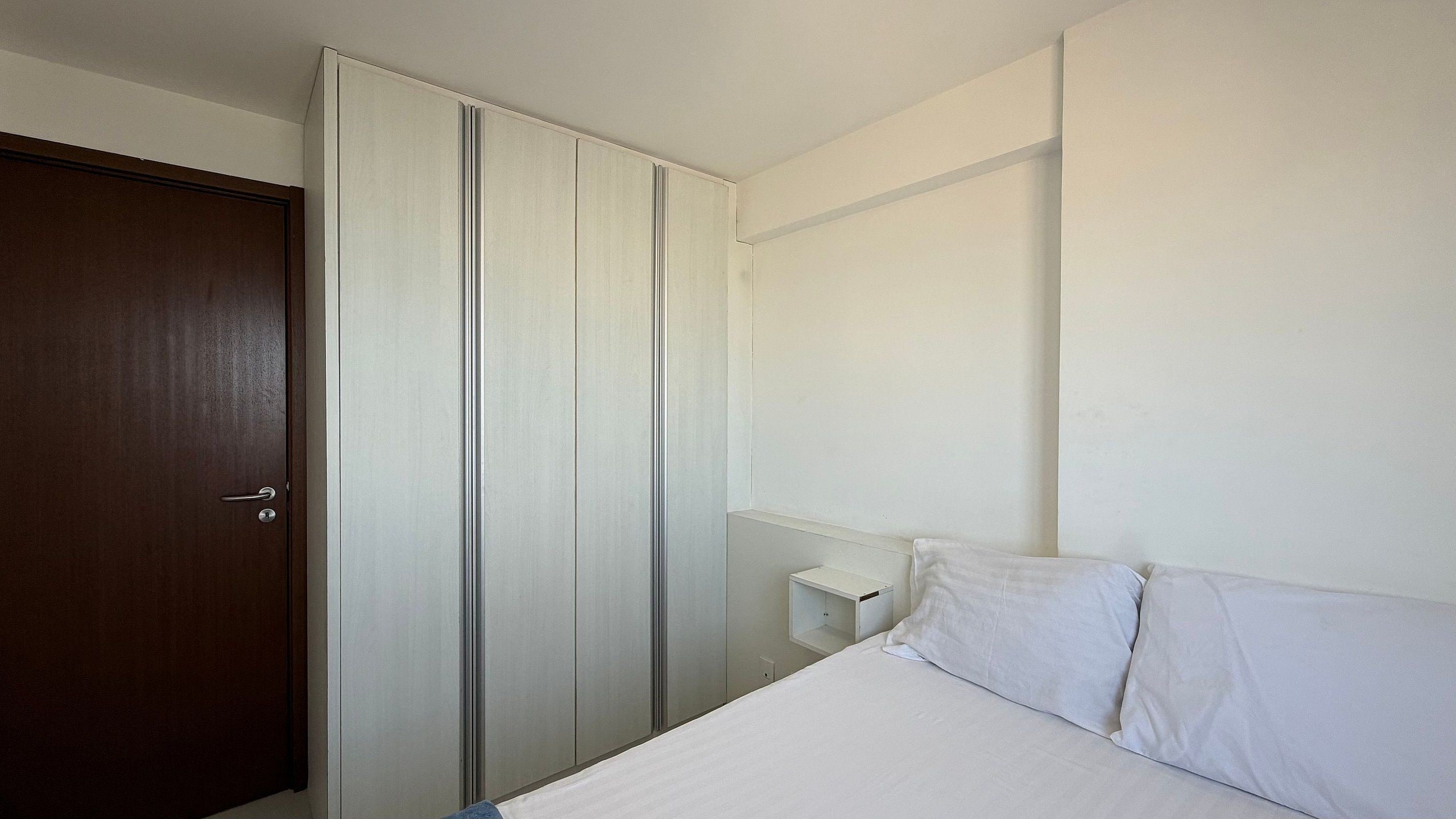 Un dormitorio con una cama, un armario y una mesita de noche.