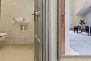 A bathroom with a toilet, sink, and tiled walls. - IMCT - Appartamento Quattroporte (Budapest)
