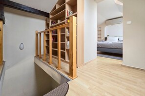 A room with a wooden bookshelf, a bed, and a door leading to another area. - Appartamento Quattroporte (Budapest)