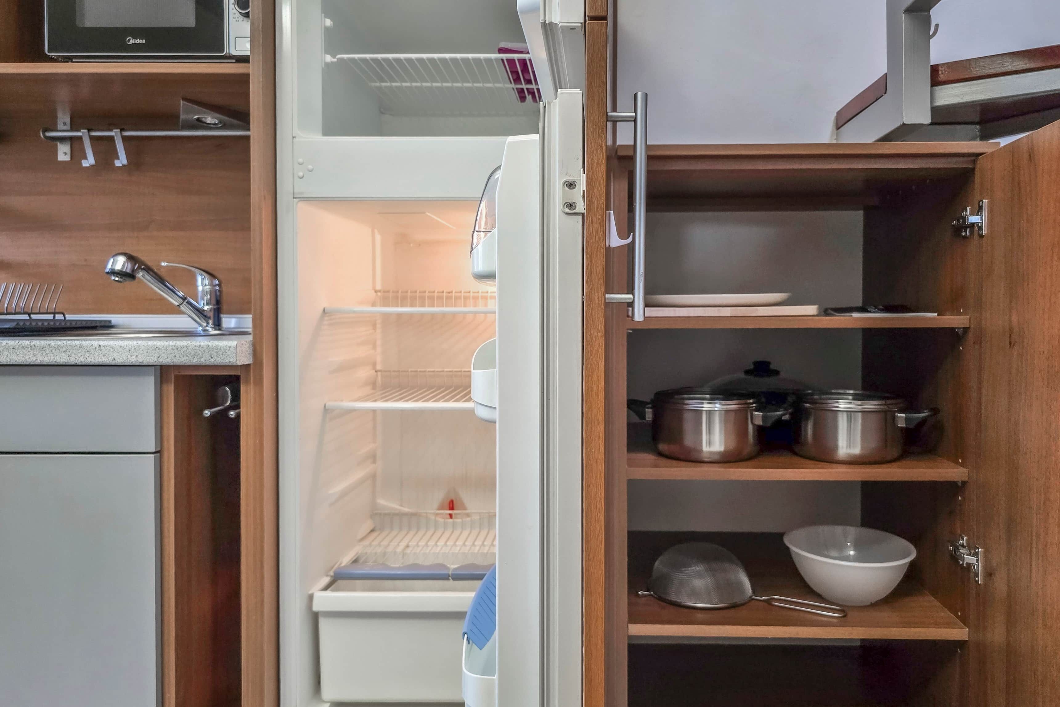 A kitchen with a built-in refrigerator, wooden cabinets, and a stainless steel sink.