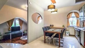 A modern kitchen with a dining area, a built-in oven, and a window with curtains. - IMCT - Appartamento Quattroporte (Budapest)