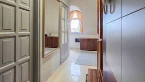 A hallway with a wooden bench, a door, and a window with curtains. - IMCT - Appartamento Quattroporte (Budapest)