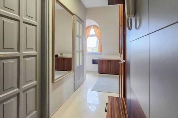 A hallway with a wooden bench, a door, and a window with curtains. - IMCT - Appartamento Quattroporte (Budapest)