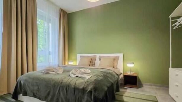 A bedroom with a bed, a nightstand, a lamp, and a dresser. - IMCT - Green Home Apartment (Törökbálint)