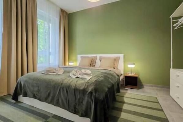 Un dormitorio con cama, mesita de noche, lámpara y cómoda.
