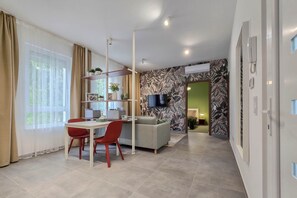 A modern living room with a dining area, a sofa, a TV, and a bookshelf.