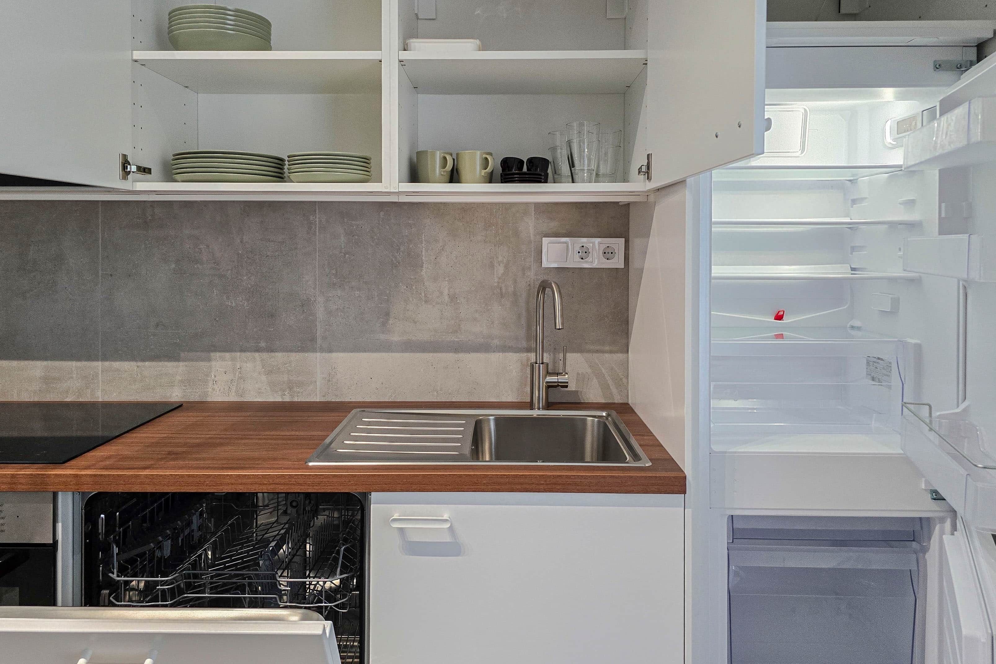 A kitchen with a built-in dishwasher, a stainless steel sink, and a wooden countertop.