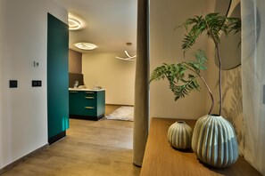 Un interior moderno con piso de madera, muebles de cocina color turquesa y una planta grande.