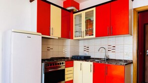 A kitchen with red and white cabinets, a stove, and a sink. - Beachfront Apartment With Stunning Sea Views (Durrës)