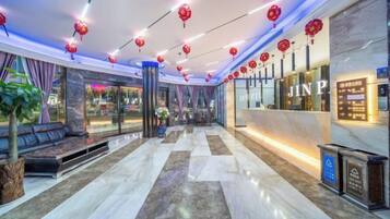Un hall d’hôtel comprenant un comptoir d’accueil, un espace salon et une grande fenêtre.