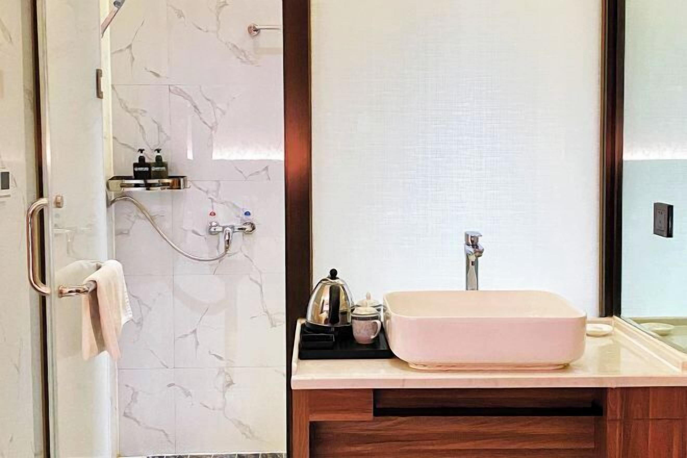 A bathroom with a marble wall, a sink with a large basin, and a towel rack.