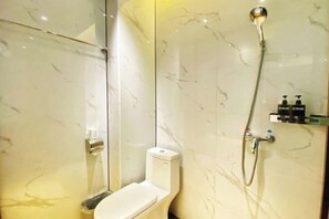 A bathroom with a toilet, a shower, and a glass partition.