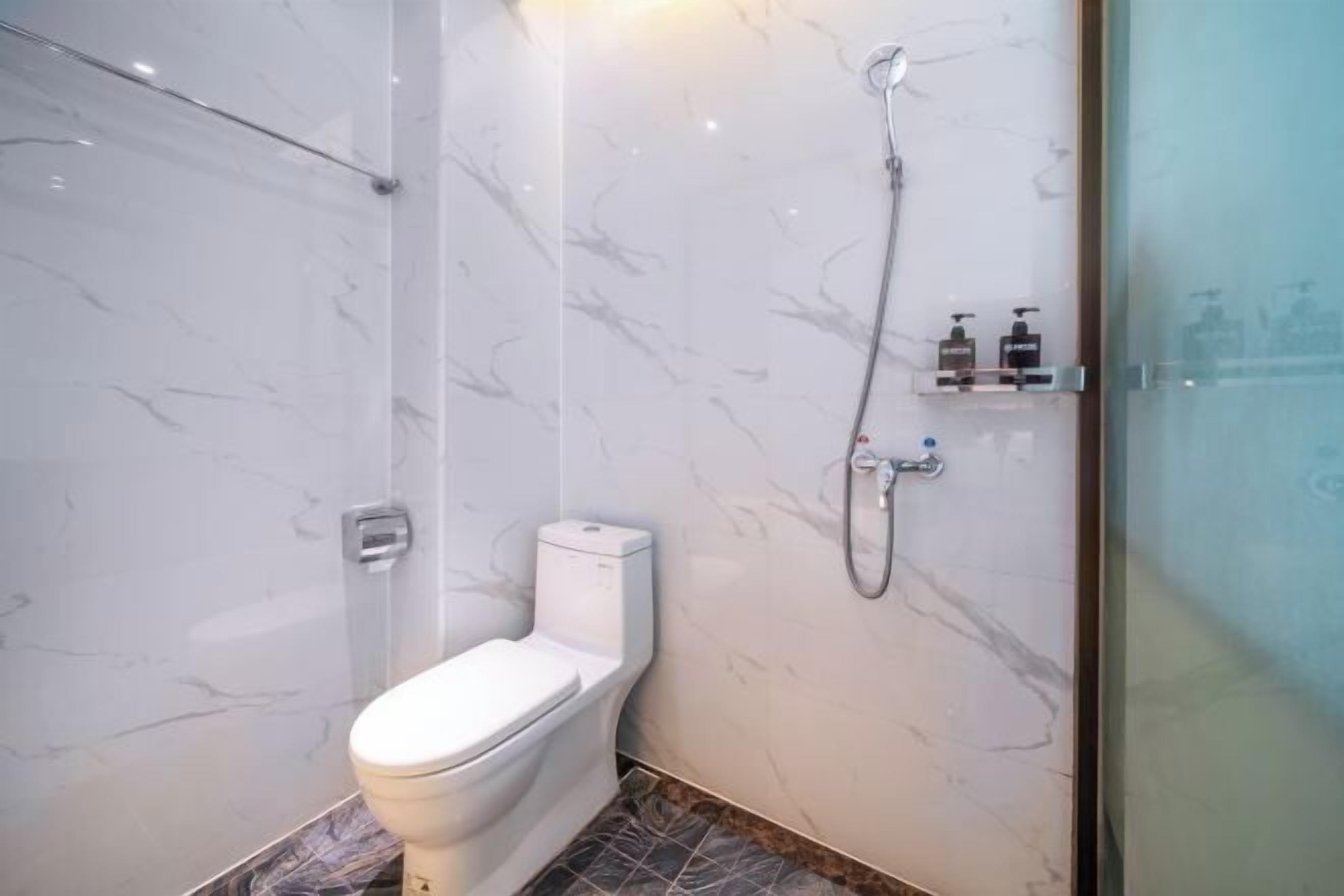 Moderni kylpyhuone, jossa on wc, suihku ja marmoriseinät.