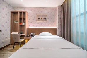 A hotel room with a bed, a desk with a chair, a wardrobe, and a window with curtains. - Gold Medal Hotel (Baise)