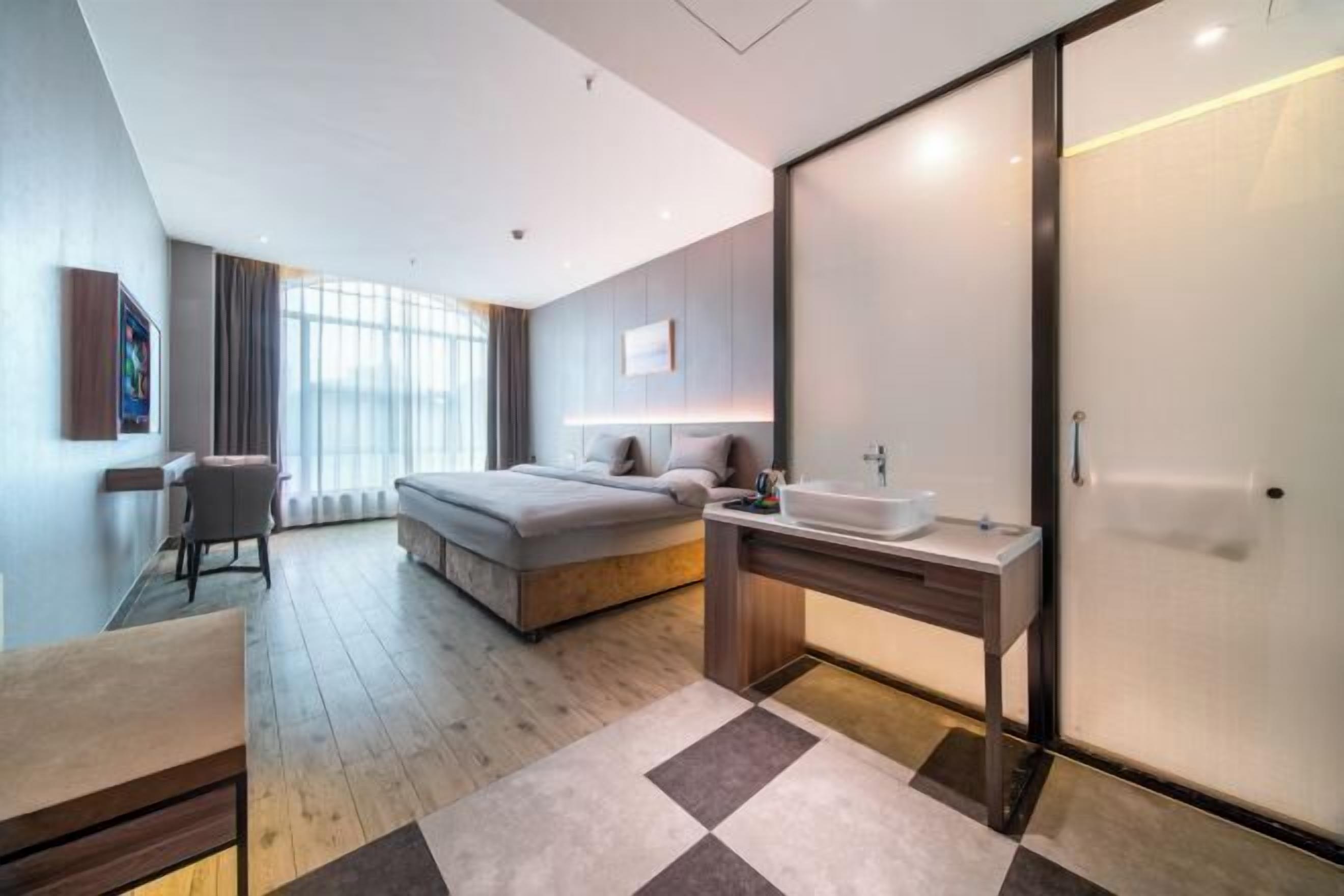 Et moderne hotelværelse med seng, sengebord og et stort vindue.