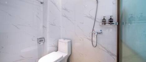A bathroom with a toilet, a shower, and a marble wall.