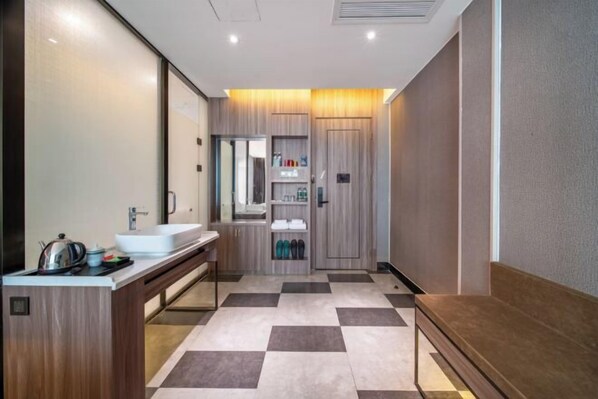 A modern bathroom with a large mirror, a sink, and a vanity. There is a shelf with toiletries and a bench. - Gold Medal Hotel (Baise)