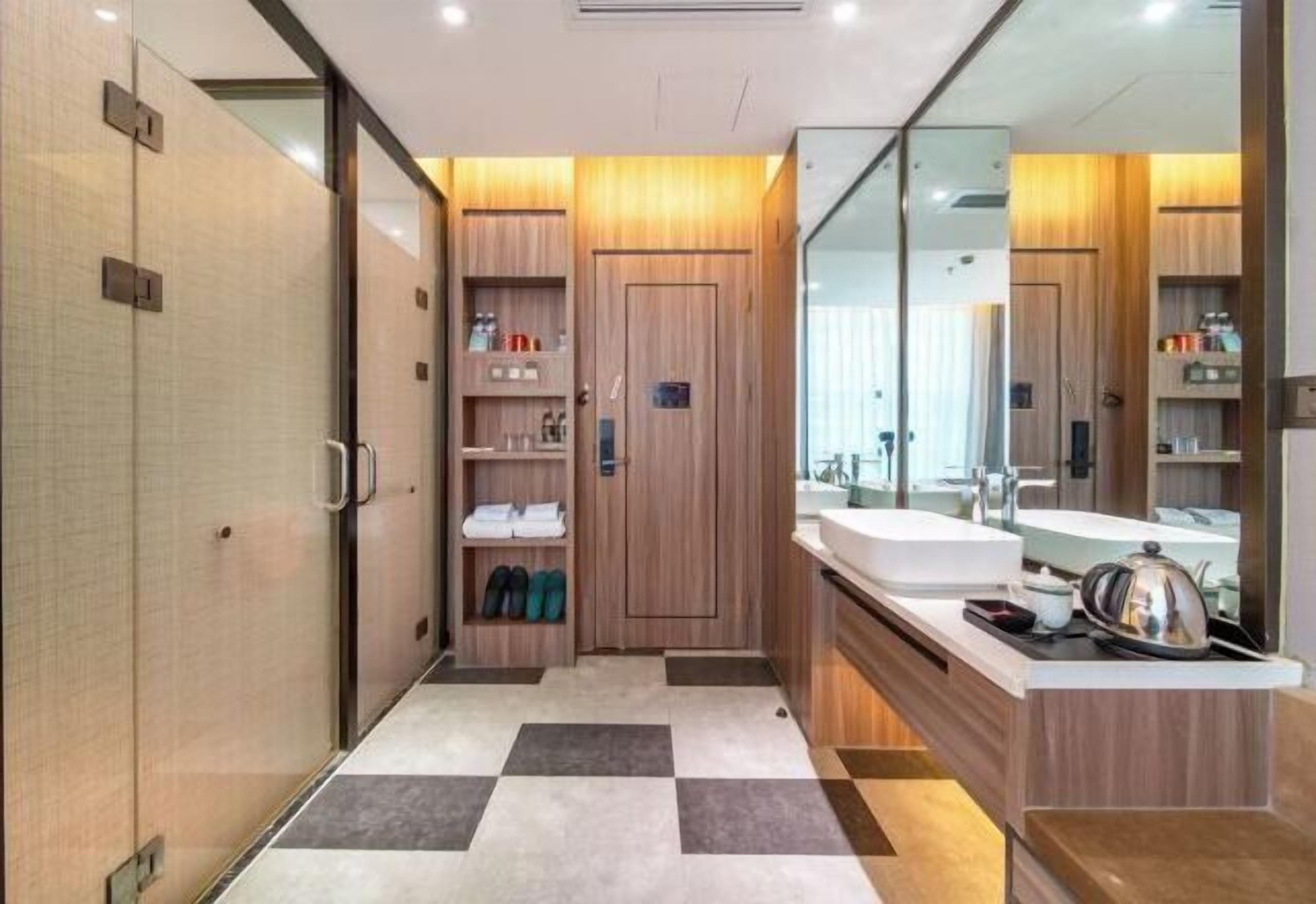 Een moderne badkamer met een geruit vloertje, houten kastjes en een grote spiegel.