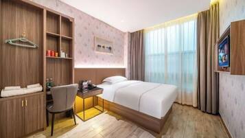 Une chambre d’hôtel équipée d’un lit, d’un bureau, d’une chaise, d’une télévision et d’une armoire.