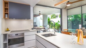 A modern kitchen with a built-in oven, a sink, and a dining area with a table and chairs.