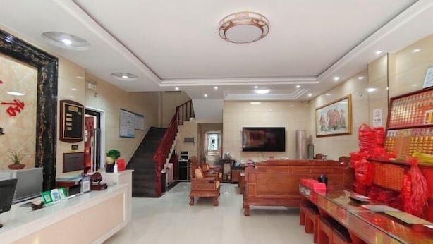 A reception area with a desk, chairs, a staircase, and a television. - Caifu Business Hotel (Hengyang)