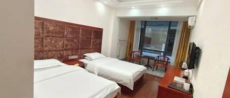 Una habitación de hotel con dos camas, un escritorio, una silla y una ventana con cortinas.
