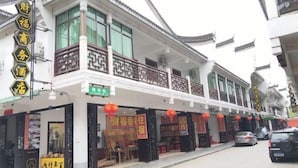 A traditional building with a covered entrance, multiple shops, and a signboard. - Caifu Business Hotel (Hengyang)