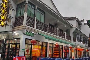 A traditional building with a balcony and multiple storefronts. - Caifu Business Hotel (Hengyang)