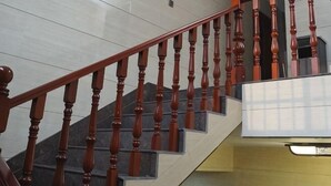 A staircase with wooden balusters and a handrail, leading to a landing with a glass door. - Caifu Business Hotel (Hengyang)
