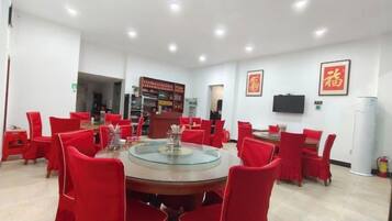 A conference room with a round table, red chairs, a television, and a vending machine.