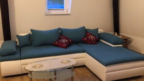 Un soggiorno moderno con un divano componibile, un tavolino in vetro e un tappeto decorato.