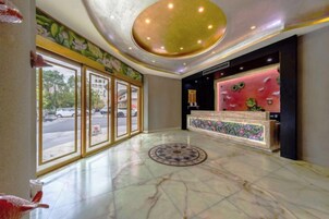 Un vestíbulo de hotel con piso de mármol, una recepción y amplios ventanales.