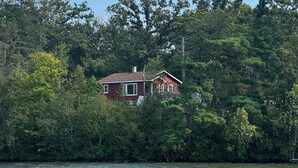 A house surrounded by dense forest and a body of water.