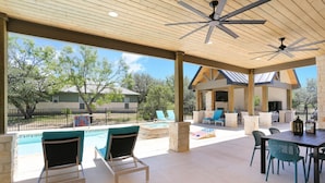 Une terrasse couverte avec une piscine, des sièges d’extérieur et une vue sur les environs.