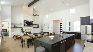 Une cuisine spacieuse dotée d’un grand îlot central, d’appareils électroménagers modernes et d’un coin repas avec des chaises.