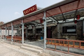 A restaurant with outdoor seating, a covered patio, and a brick wall. - Beijing Chenshuang Restaurant (Beijing)
