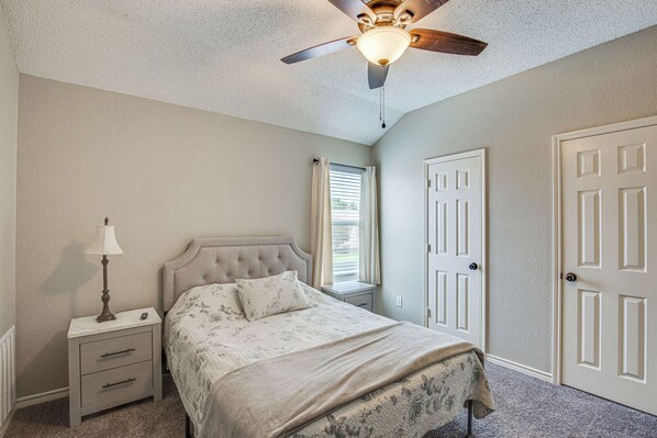 A bedroom with a bed, nightstand, lamp, ceiling fan, and two doors. - Pet-Friendly Allen Home ~ 30 Mi to Dallas! (Allen)