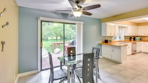 A kitchen with a glass dining table, white cabinets, and a ceiling fan. - 5 Mi to Warren Dunes - Secluded Sawyer Home! (Sawyer)