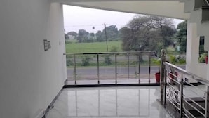A spacious room with a marble floor, a view of a road and greenery, and a balcony with a railing. - Hotel Moonlight & Restaurant (Sehore)
