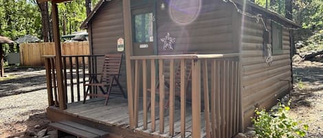 A wooden cabin with a porch, a chair, and a small staircase leading to the entrance.