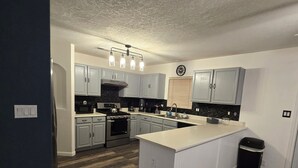 A modern kitchen with light gray cabinets, a central island, and a stainless steel refrigerator. - Charming 4-bedroom house with beautiful backyard and mountain view. (Albuquerque)