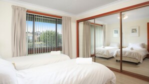 Une chambre d’hôtel avec deux lits, une porte-fenêtre coulissante et une vue sur l’extérieur.