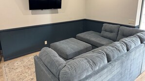 A living room with a grey sectional sofa, a flat-screen TV mounted on the wall, and a patterned rug on the floor. - The Lawft, Suite 2, 2 King beds each with own bathroom, No Clean fees,No Pets (Russell)