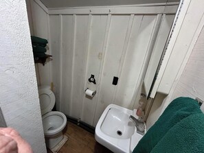 A small, narrow bathroom with a toilet, sink, and a towel rack.